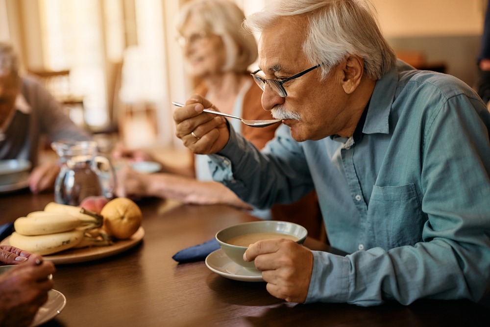 Mature,Man,Eating,Soup,While,Having,Lunch,At,Residential,Care